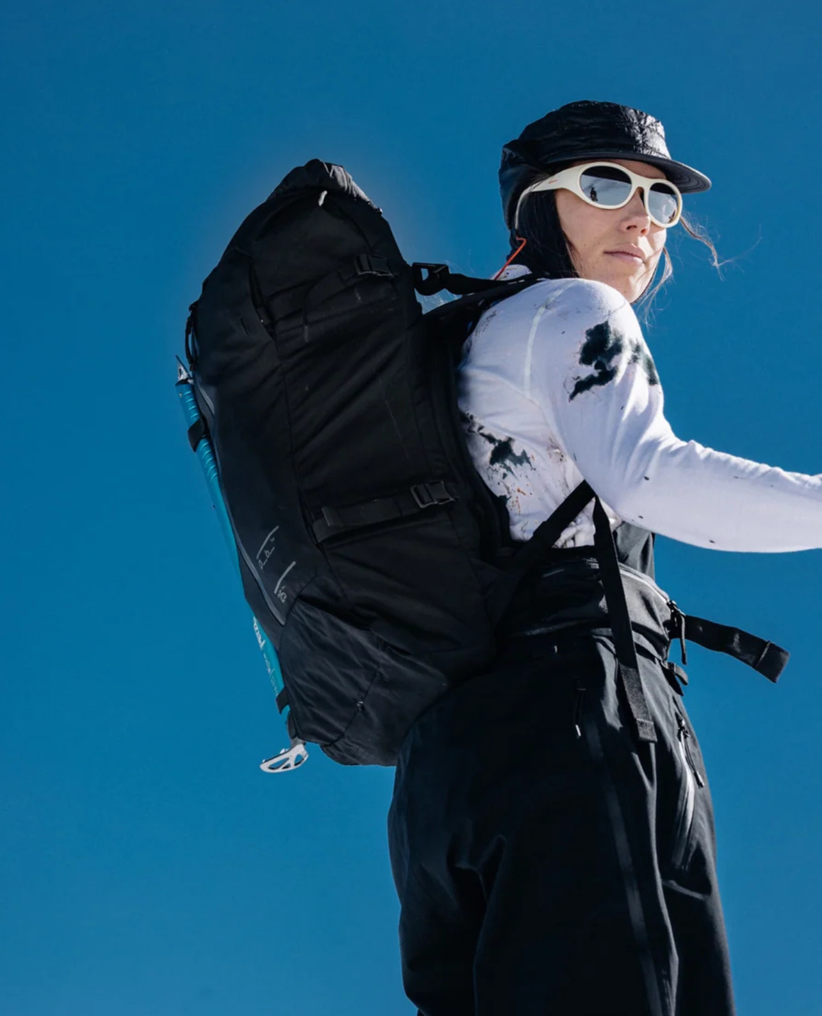 D_b_ Snow Pro Backpack 25L i svart med skidåkare mot blå himmel.
