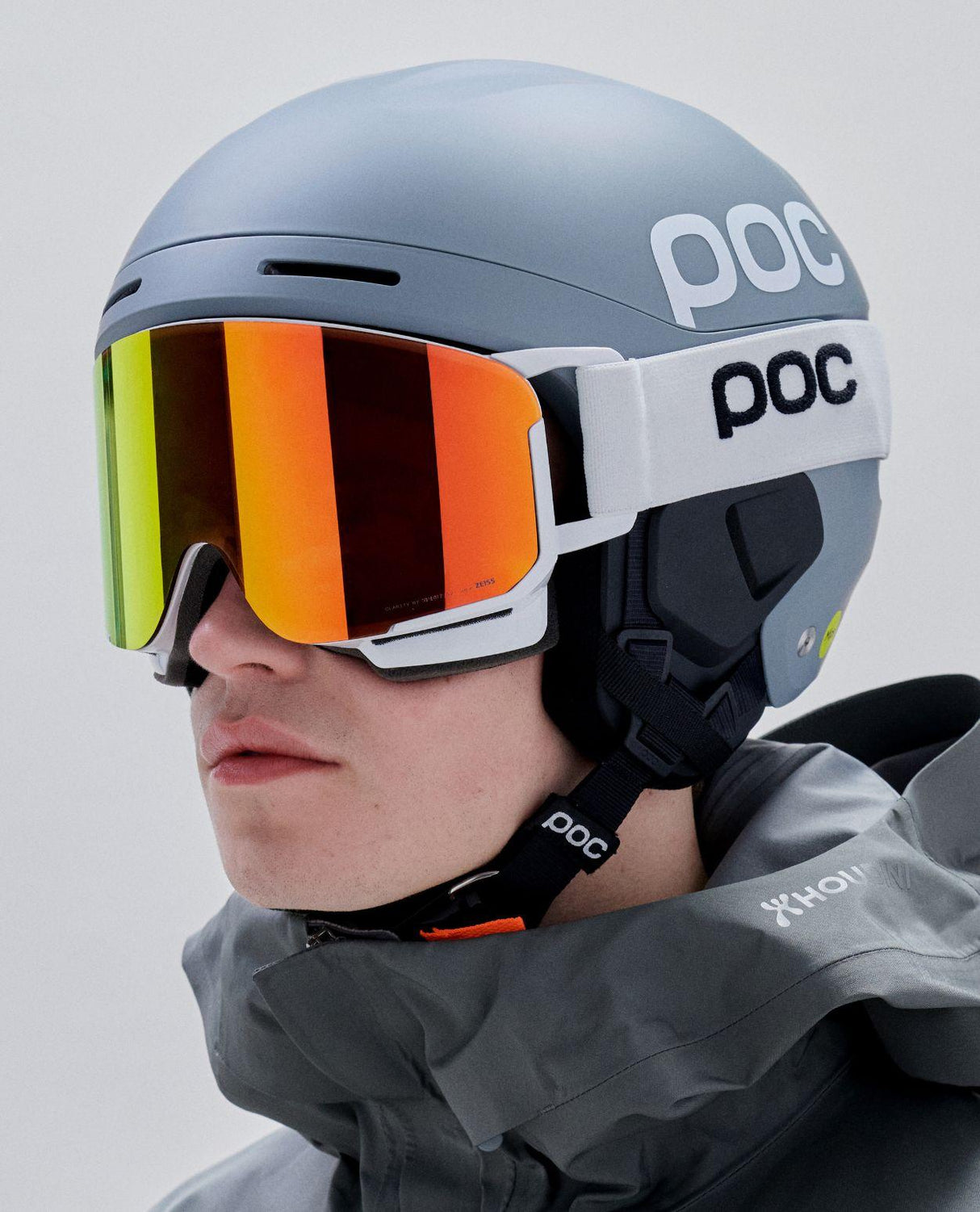 Skidåkare i profil som bär POC Nexal skidglasögon i Hydrogen White med orange spegellins tillsammans med en matchande POC-hjälm.