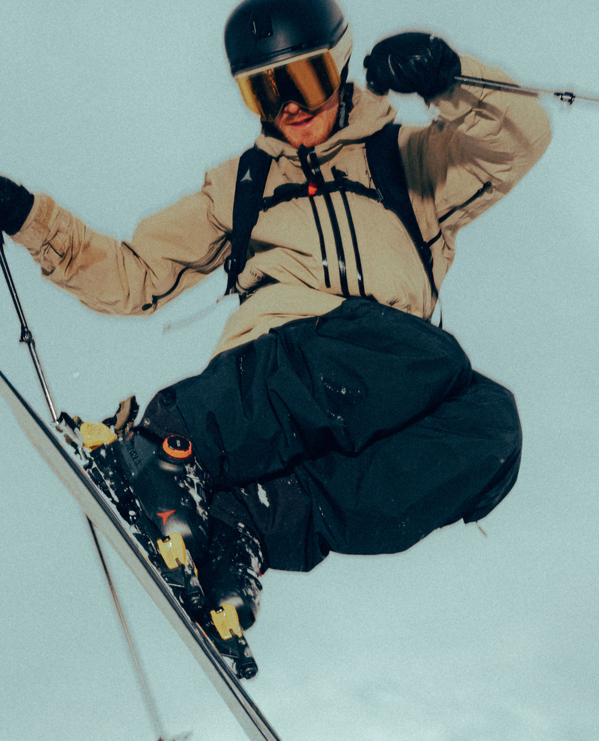 Alpinskidåkare i luften med Atomic Hawx Prime 130 S BOA pjäxor, beige skaljacka och svarta skidbyxor.