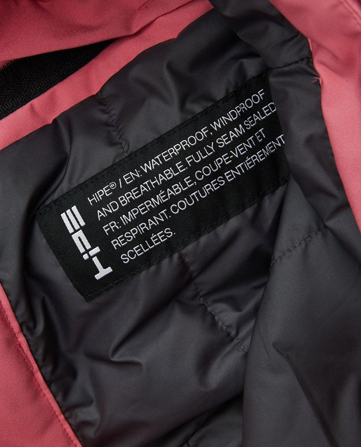 Närbild på inneretikett som visar HIPE-materialets egenskaper i Peak Performance Gravity Insulated skidbyxor för juniorer.
