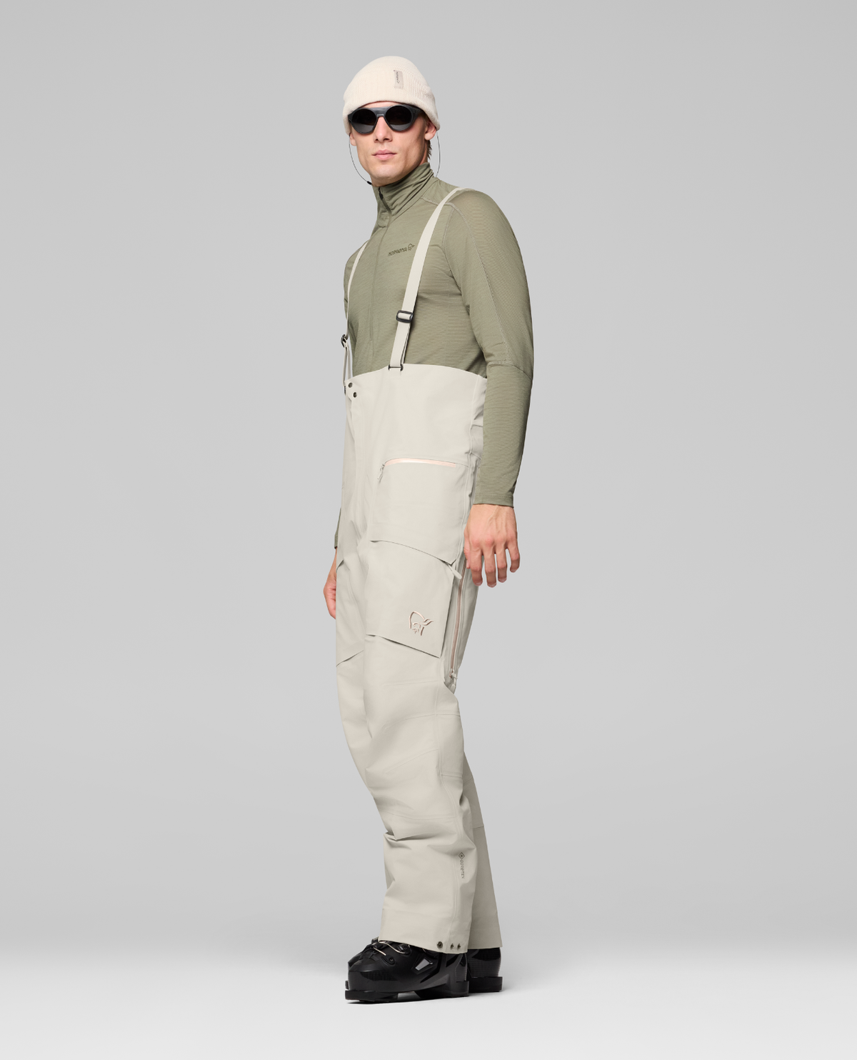 Norrøna Møre Gore-Tex Salopette Men i färg oatmeal för herrar på modell sedd från sidan. Alpingaraget