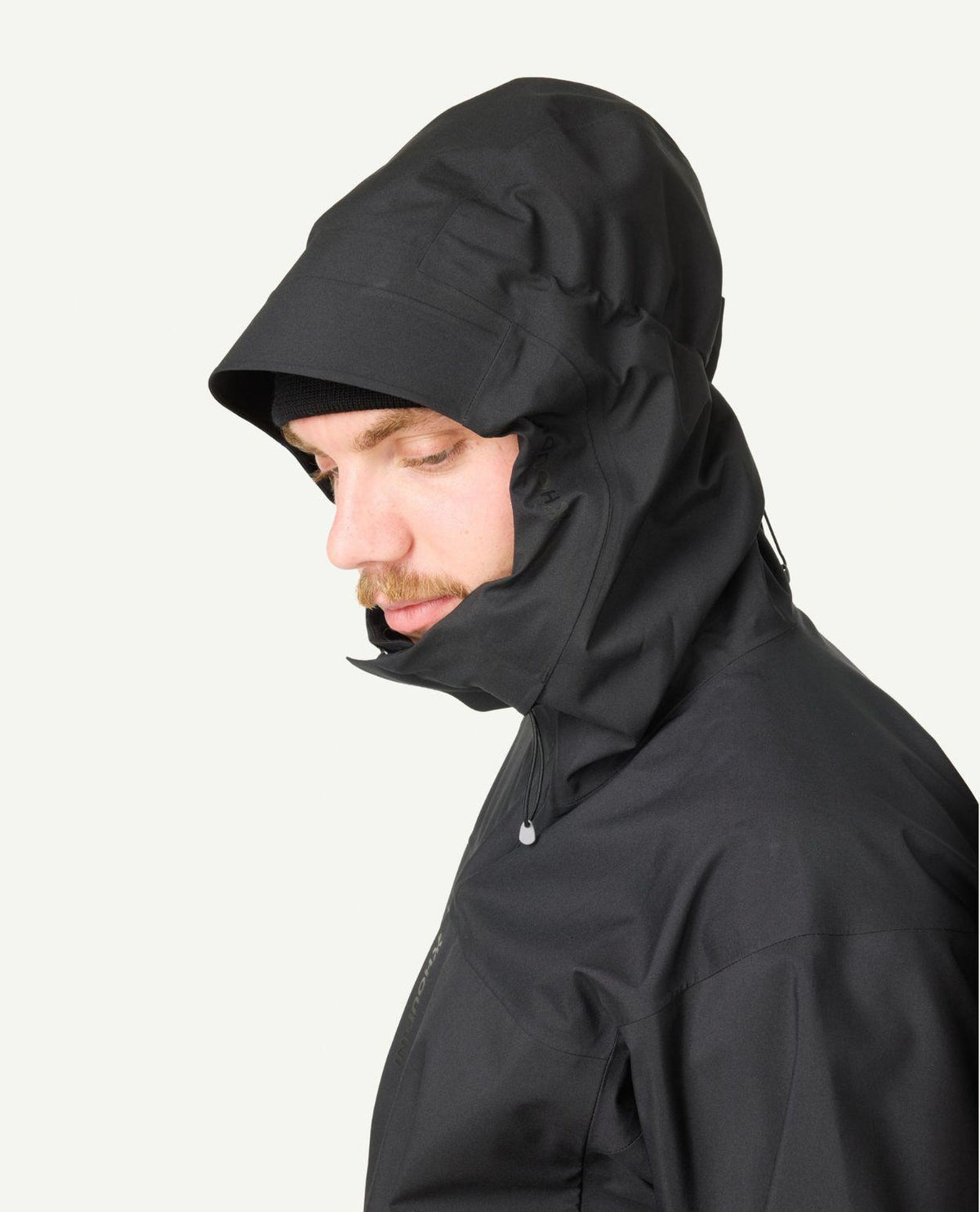 Manlig skidåkare iförd den svarta Houdini Rollercoaster Jacket II med huvan uppdragen.