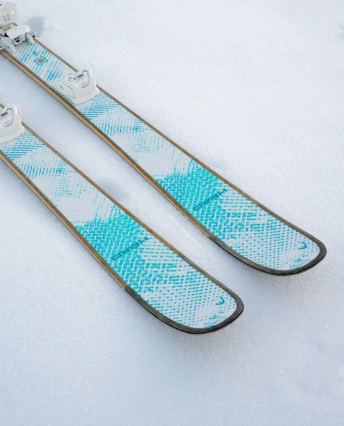 Head Kore 93 Ti Women allmountainskidor i vit design med turkosa detaljer liggandes i snö.