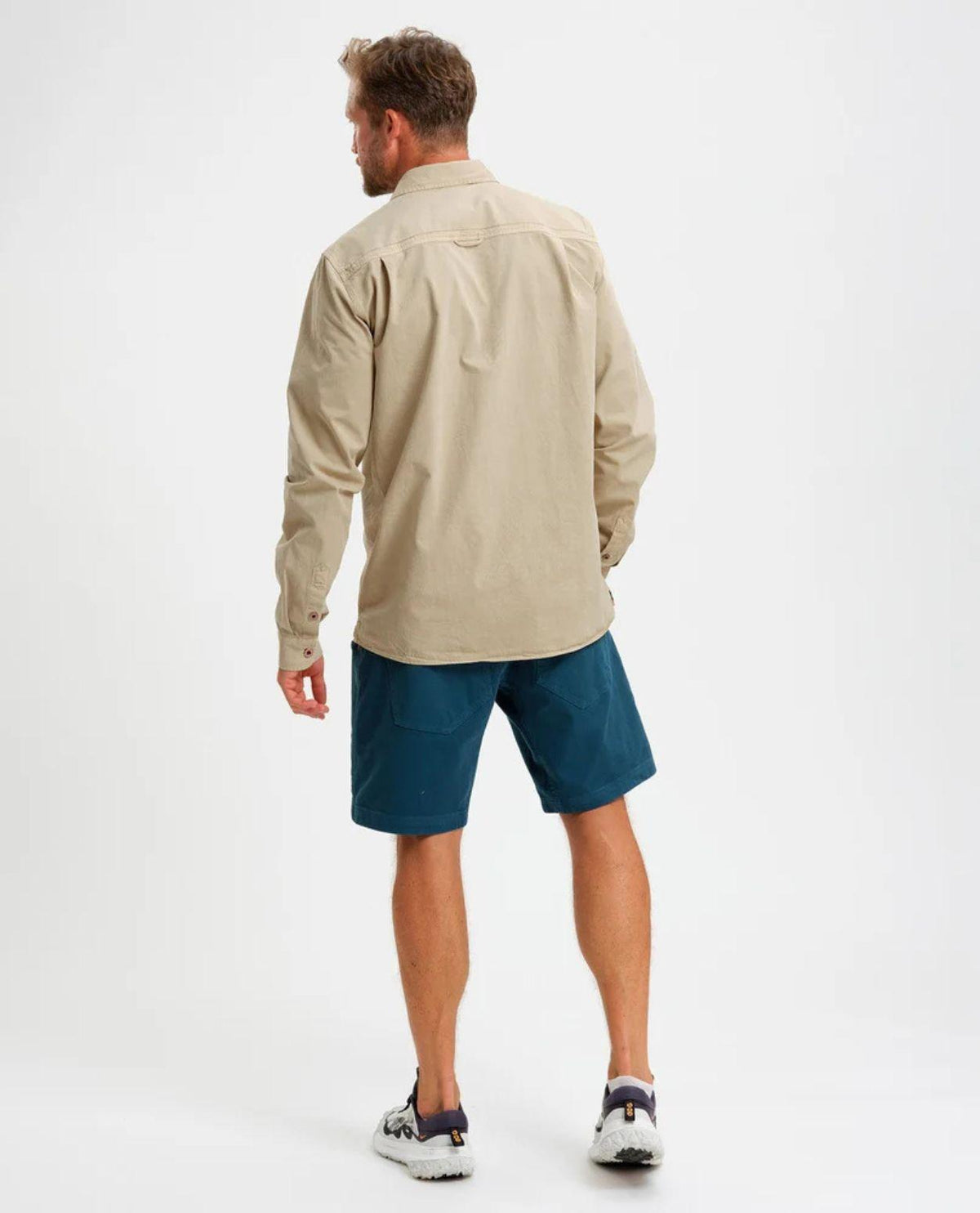 Man som bär Elevenate Utility Shirt i färgen Safari och blå shorts sedd bakifrån.