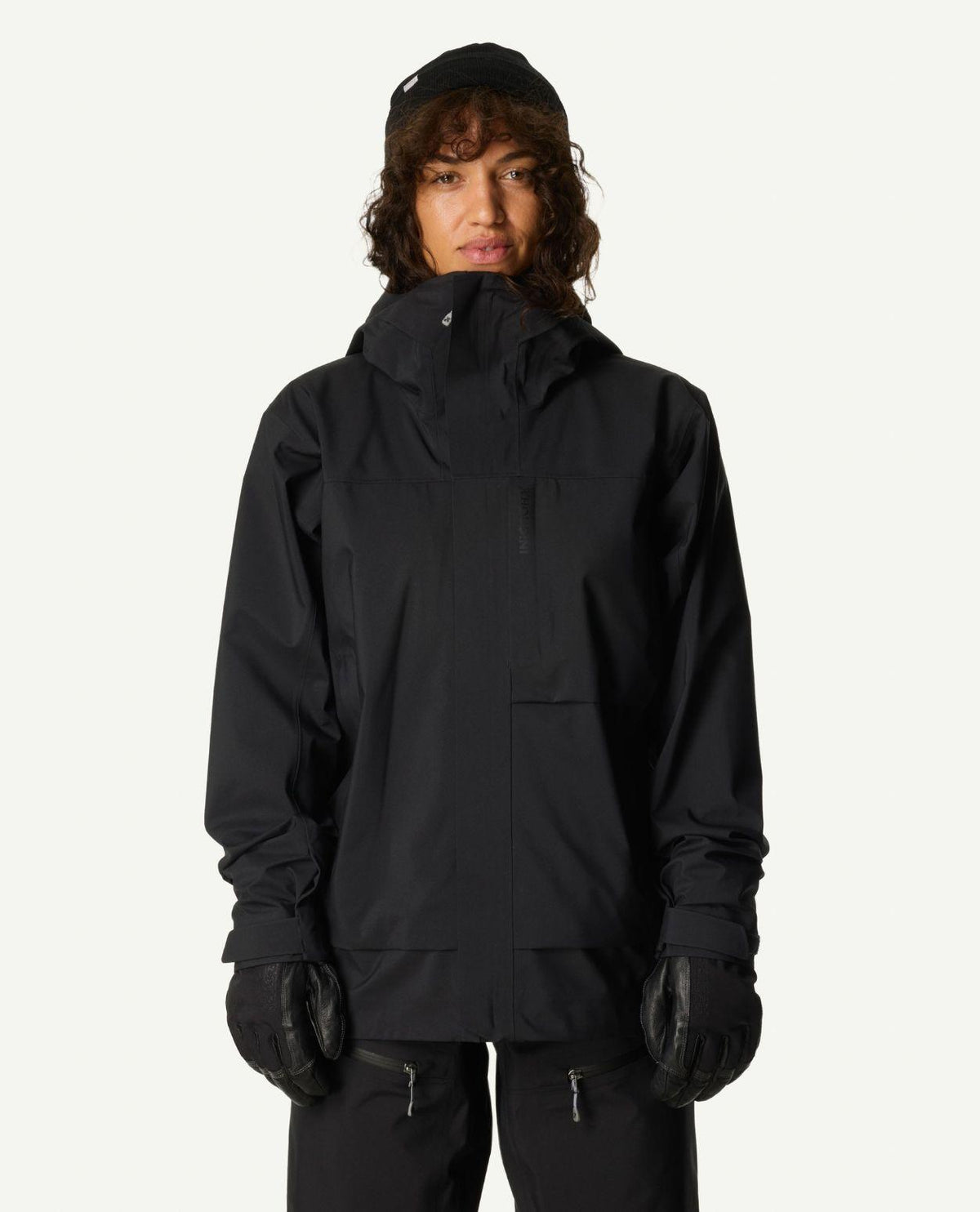 Kvinna iklädd Houdini Rollercoaster Jacket II i färgen True Black med tillhörande skidbyxor och svarta handskar.