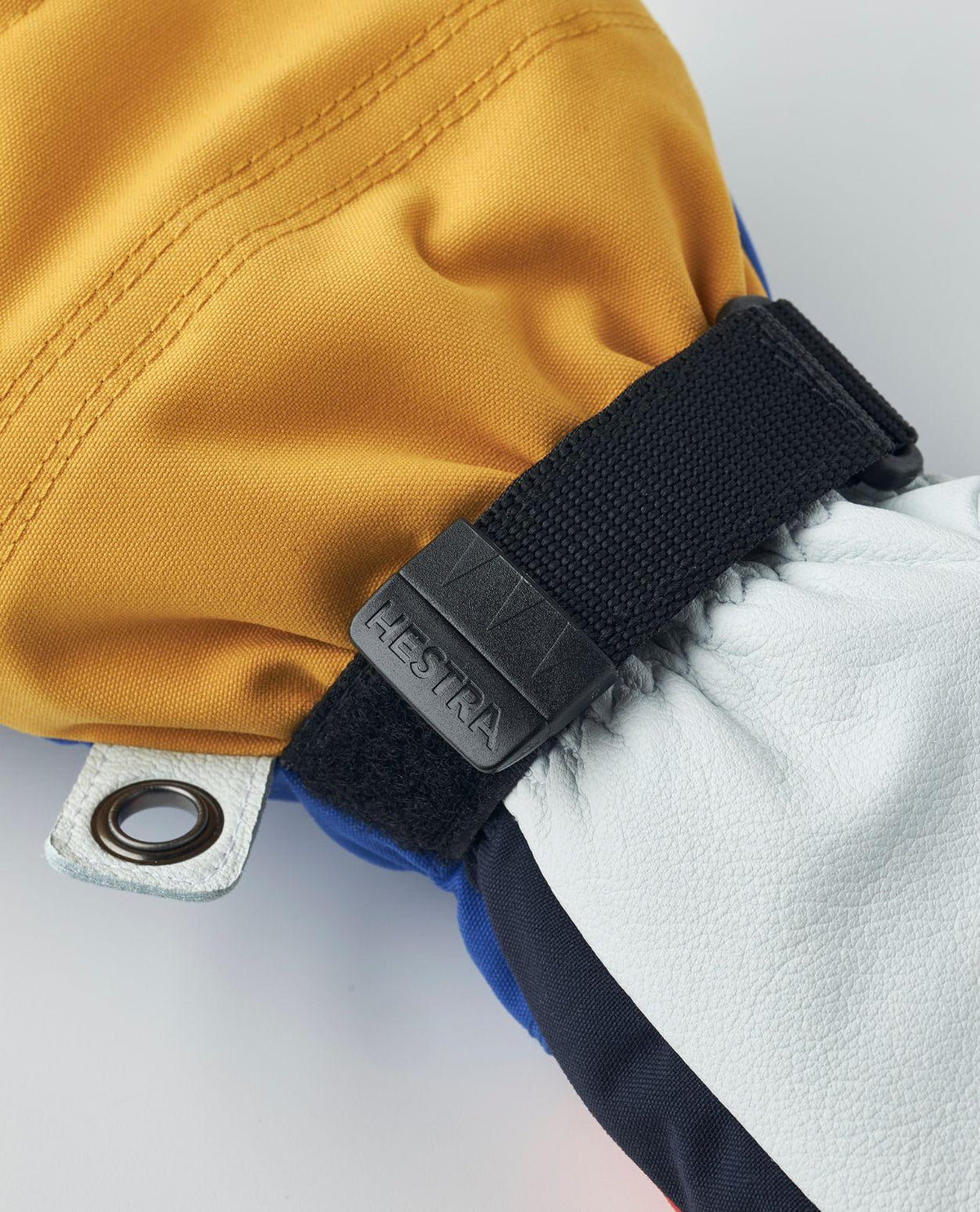 Närbild på handledsrem och spänne med Hestra-logotyp på Hestra Army Leather Heli Ski Mitt skidhandskar.