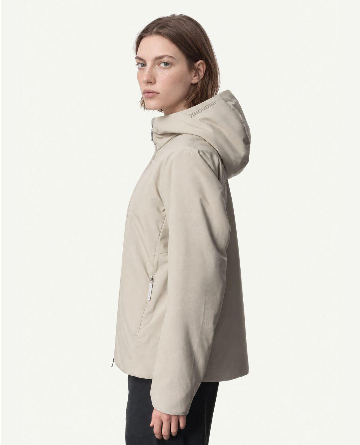 Kvinna i profil som bär Houdini Tech Insulation Houdi i färgen sandstorm.
