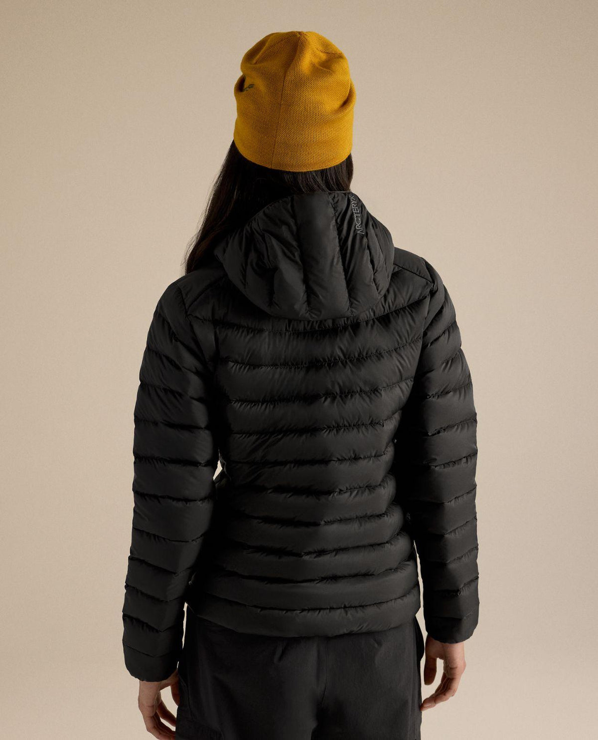Arc'teryx Cerium Hoody Women i svart bärs bakifrån med huva och gul mössa.