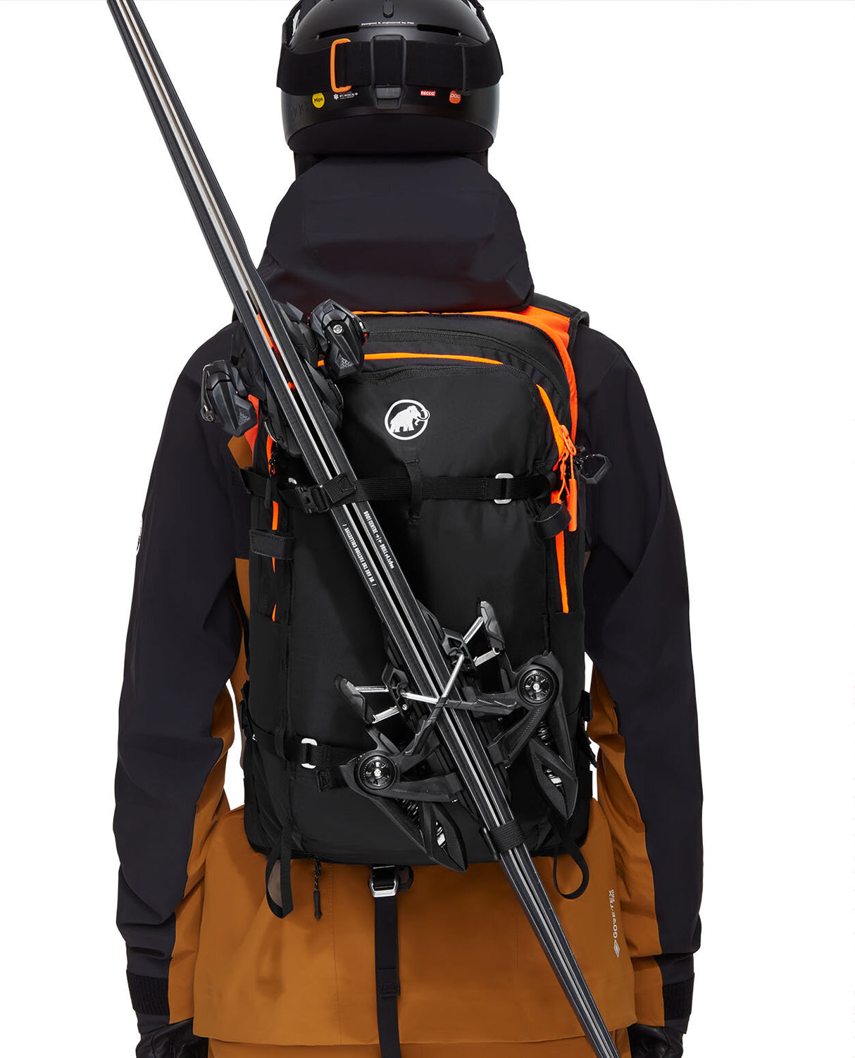 En skidåkare sedd bakifrån bärandes en svart Mammut Free 28 Removable Airbag 3.0 lavinryggsäck med skidor fastspända diagonalt.