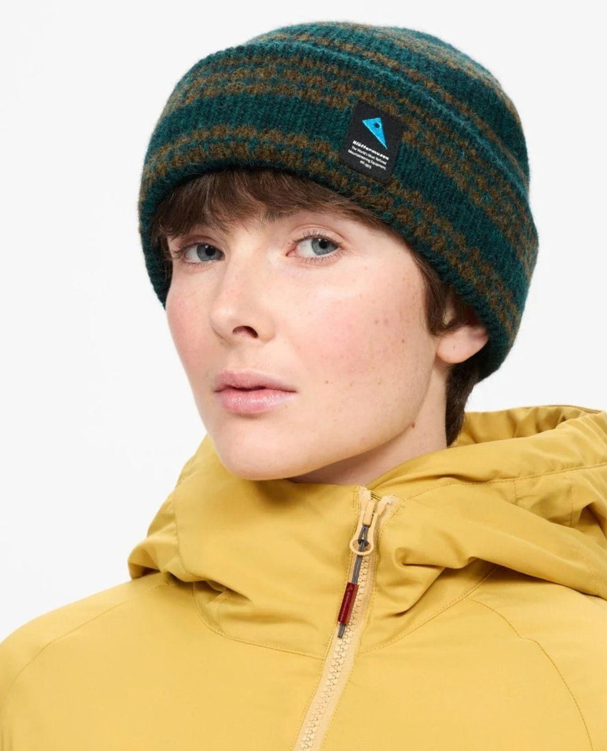 Klättermusen Runa Bandr Beanie i grön ullblandning på modell med gul jacka.