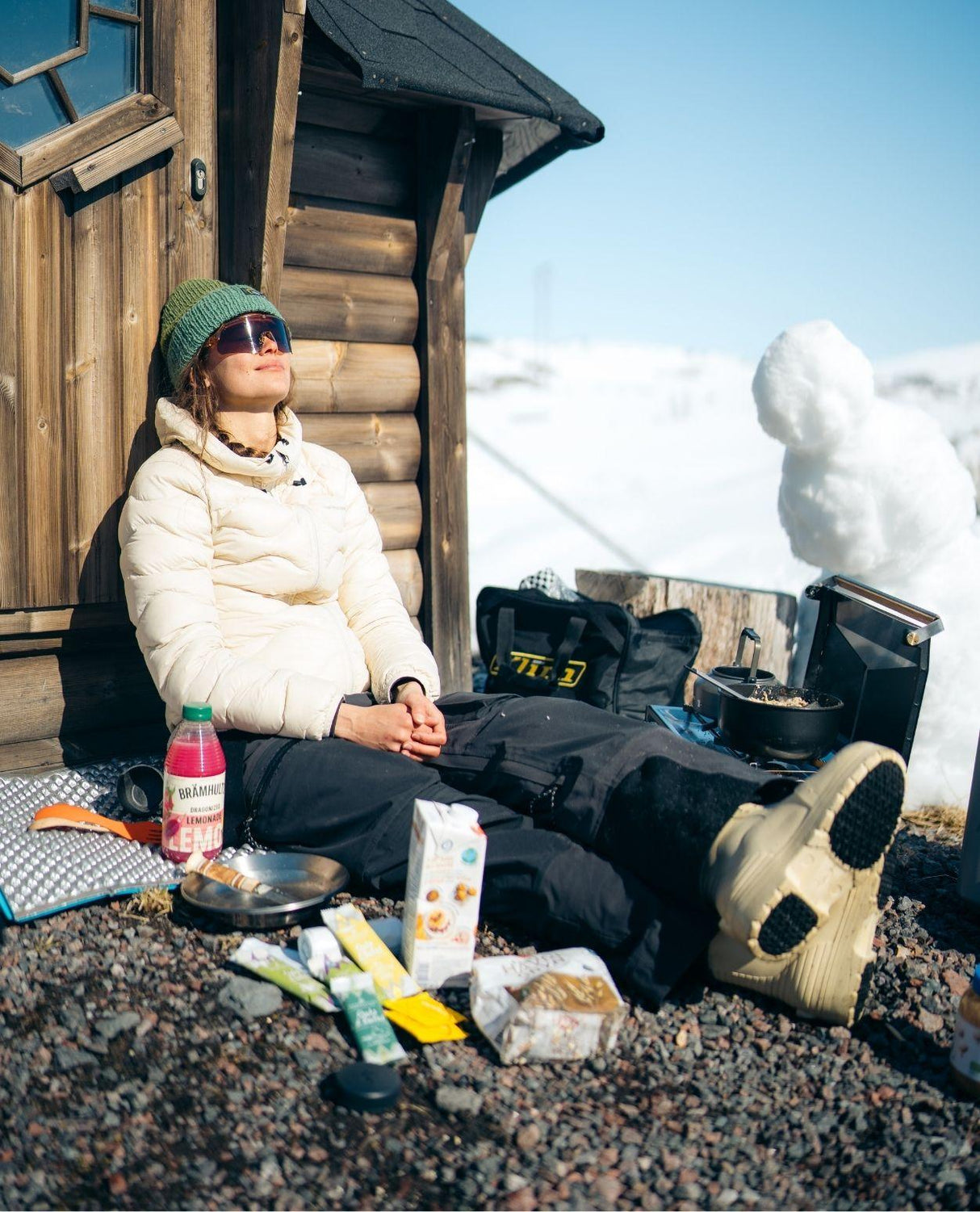 Skidåkare som njuter i solen mot en trävägg iklädd FUBUKI Niseko 3.0 Low vinterkängor i sandfärg.