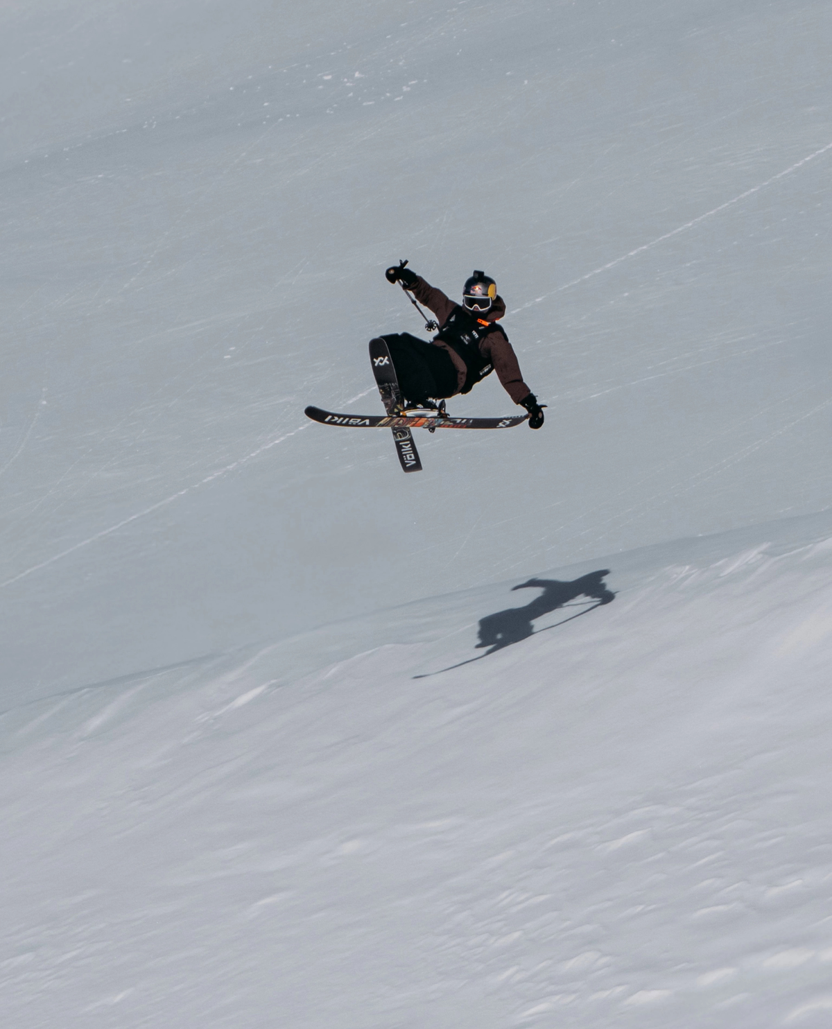 Skidåkare i luften som utför ett hopp med Völkl Revolt 86 parkskidor i ett snöigt bergslandskap.