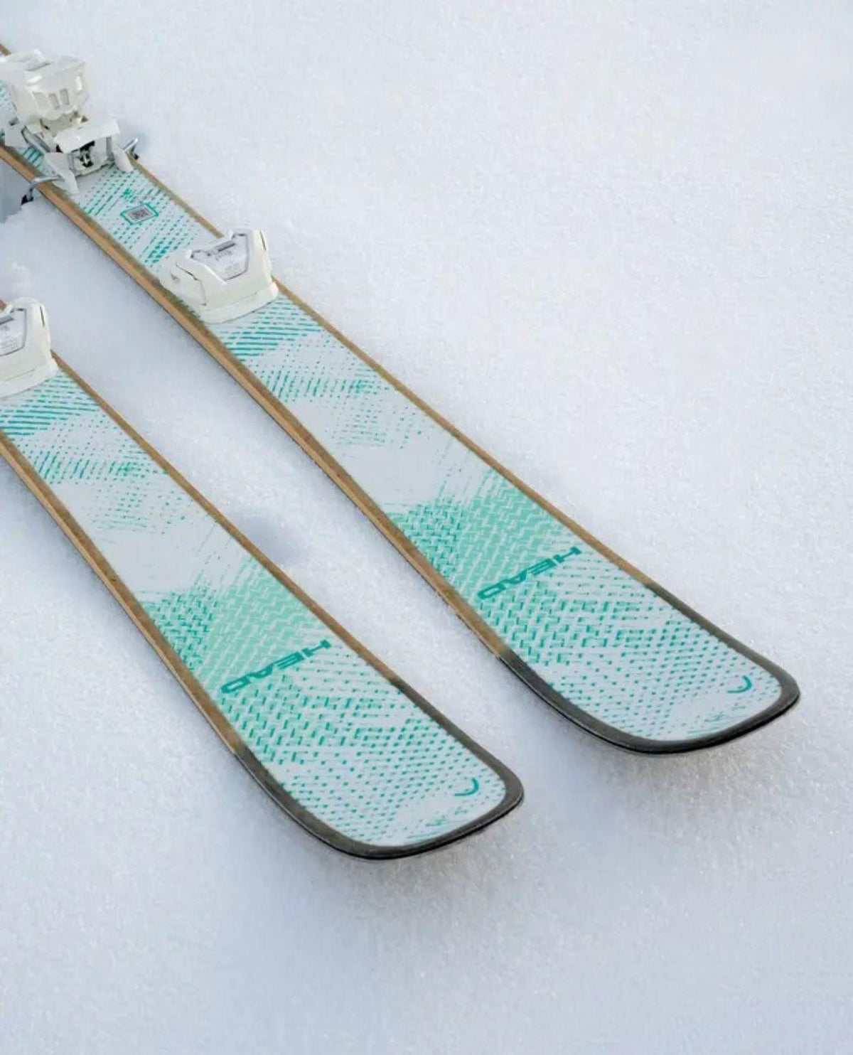 Head Kore 87 Ti Women freerideskidor i vitt och turkost placerade i snön.