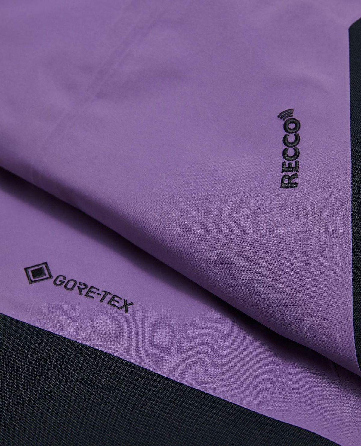 Närbild på Gore-Tex- och Recco-detaljer på lila damturskidbyxor från Peak Performance.