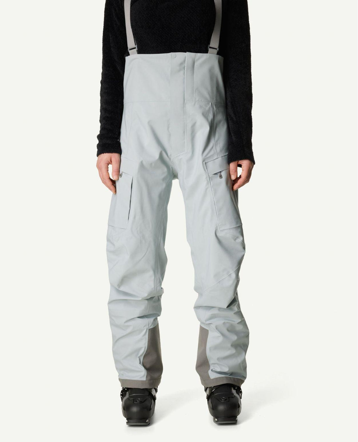 Houdini Rollercoaster Bib Pants II Women i grå färg på dammodell bärandes skidbyxor och pjäxor.