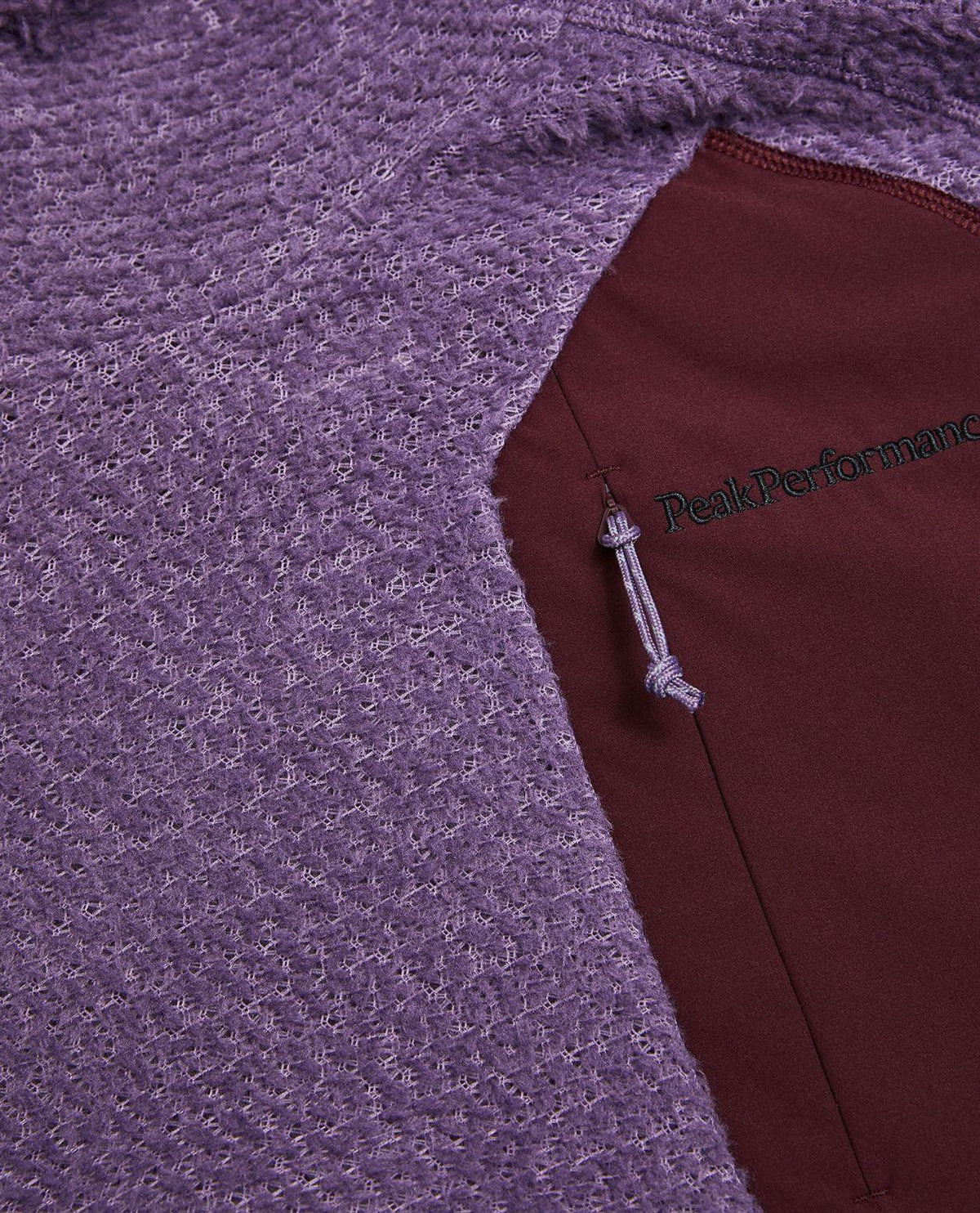 Detaljbild på bröstfickan av lila skidjacka Peak Performance Freelight Alpha Hood Women i strukturerat material.
