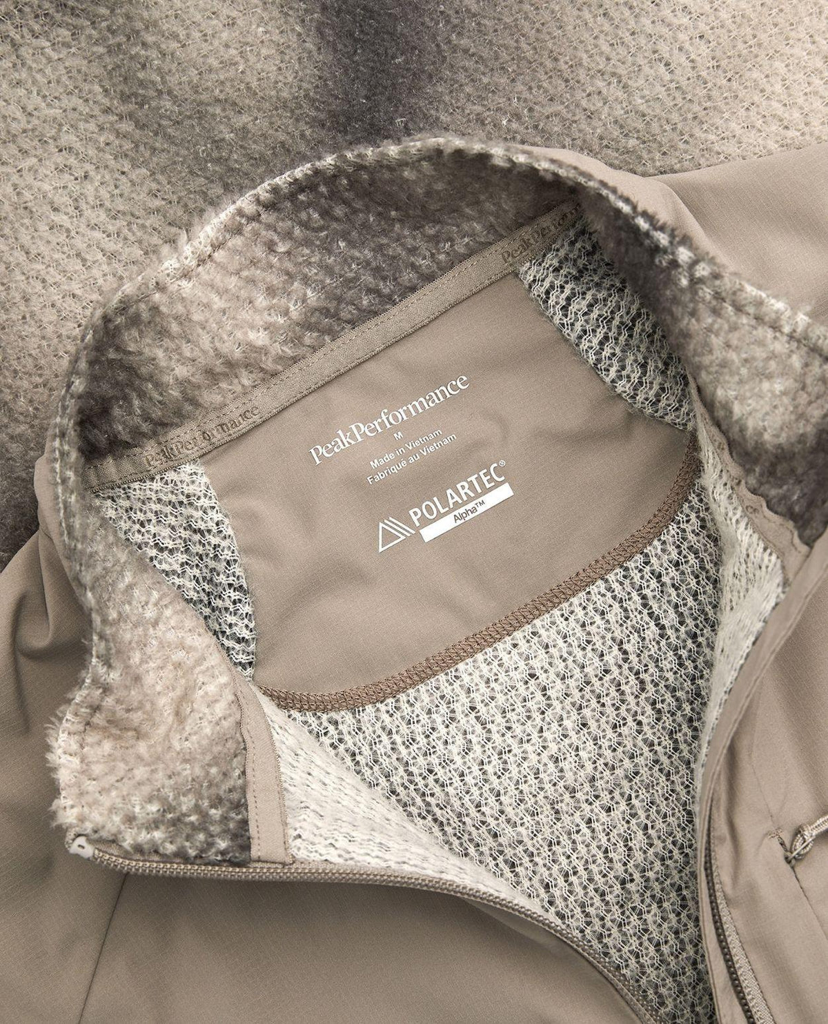Närbild på insidan och kragen av Peak Performance AOP Freelight Alpha Half Zip Men i färgen Ray, som visar Polartec Alpha-materialet.