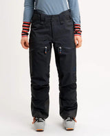 Elevenate Pure Pants Women i mörksvart färg framifrån, visande skidbyxornas passform, dragkedjor och förstärkta benslut.