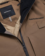 Detaljbild på bruna Peak Performance Alpine Gore-Tex Insulated Jacket för herrar som visar logotypen och dragkedjan.