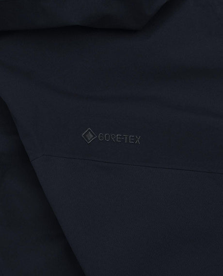 Detaljbild på den svarta Gore-Tex-logotypen på Peak Performance Alpine Gore-Tex Insulated skidbyxor för herr.