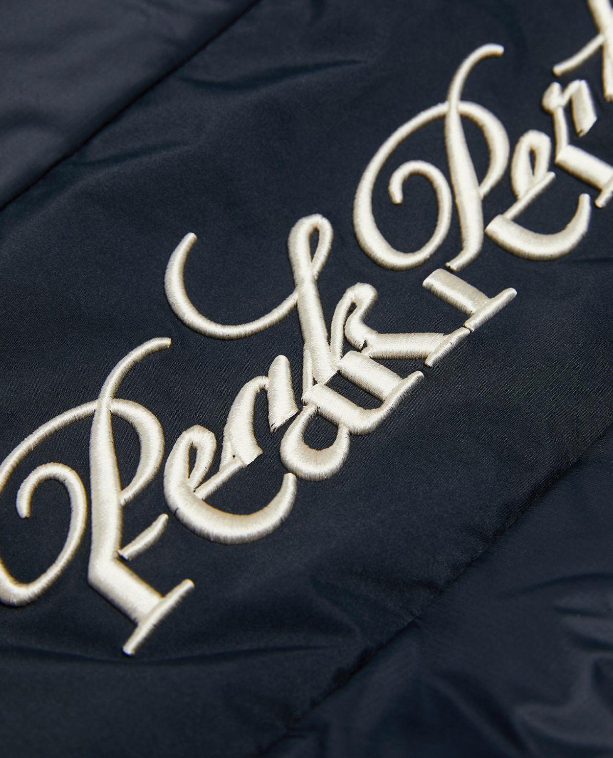 Närbild på den broderade Peak Performance-logotypen på den svarta dam skidjackan.