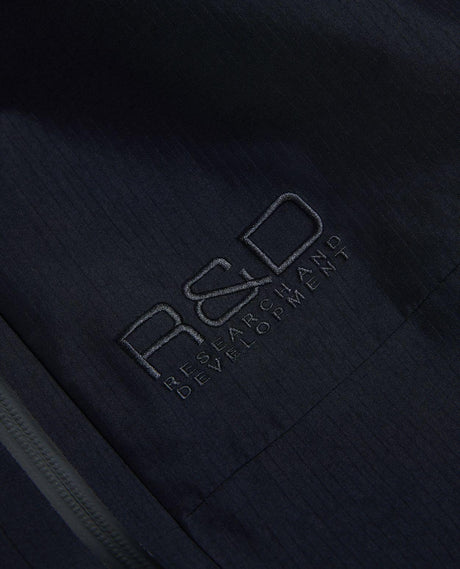 Detaljbild på broderad R&D-logotyp på svarta skidbyxor från Peak Performance.