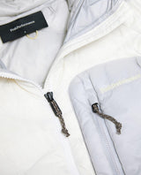 Närbild på Peak Performance Helium Utility Down Hood Jacket Dam i offwhite och antarktisgrå med dragkedja.