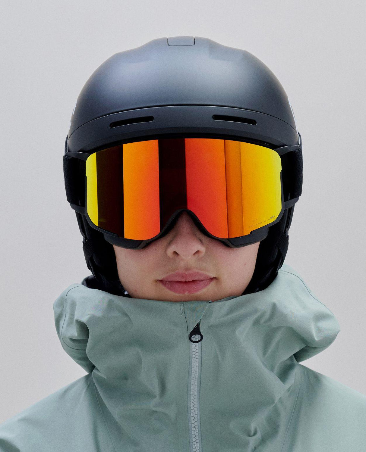POC Nexal Mid skidglasögon i Uranium Black med orange spegellins på skidåkare.