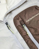 Närbild på bröstficka och dragkedja på Peak Performance Helium Utility Down Hood Jacket i färgerna Antarctica och Terrain Tan.
