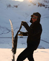 Skidåkare i soligt alpint landskap som drar av stighudar från en Extrem Ski Co Drifter 102 skida.