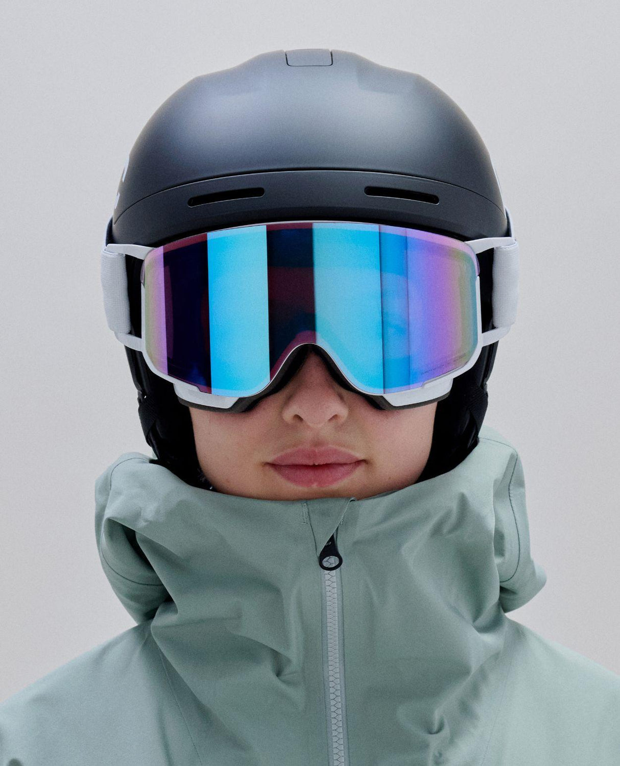 POC Nexal Mid skidglasögon i färg Hydrogen White med speglande Partly Sunny Blue-lins bärs tillsammans med mörk hjälm.