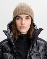 J.Lindeberg Vale Beanie i brun färg som bärs av modell i svart jacka.