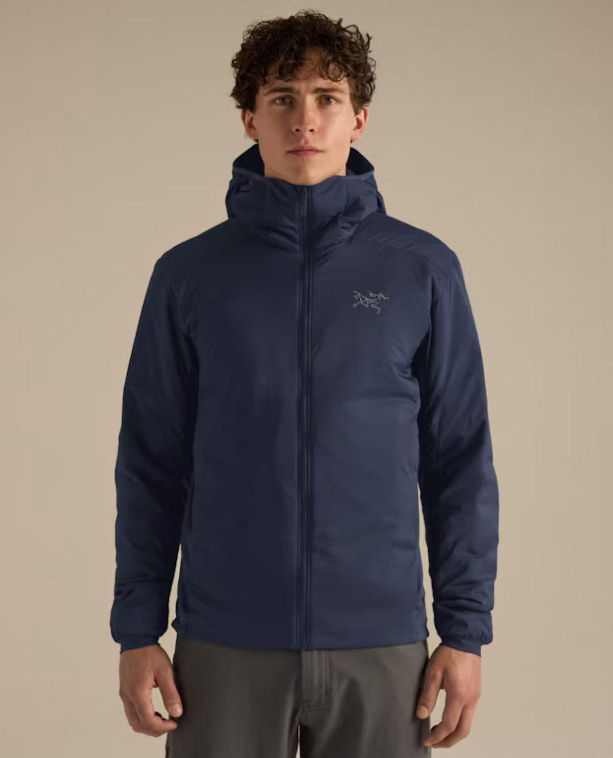 Manlig modell bär Arc'teryx Atom Hoody i blå färg med uppfälld huva framifrån.