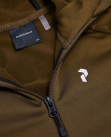 Peak Performance Rider Essentials Zip Hood Junior i grön Meadow Moss visar bröstdetaljer och logotyp.