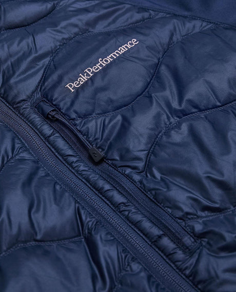 Närbild på Peak Performance Helium Down Hybrid Jacket i blått som visar bröstficka och logotyp.