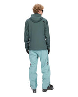 Klättermusen Drifa Hood Jacket i färgen Dark Teal för herr, visad bakifrån på skidåkare.