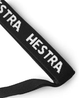 Närbild på svart Hestra Handcuff handledsrem med vit invävd logo för skidhandskar.