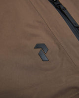 Närbild på Peak Performance-logotypen på bruna skidbyxor i Gore-Tex.
