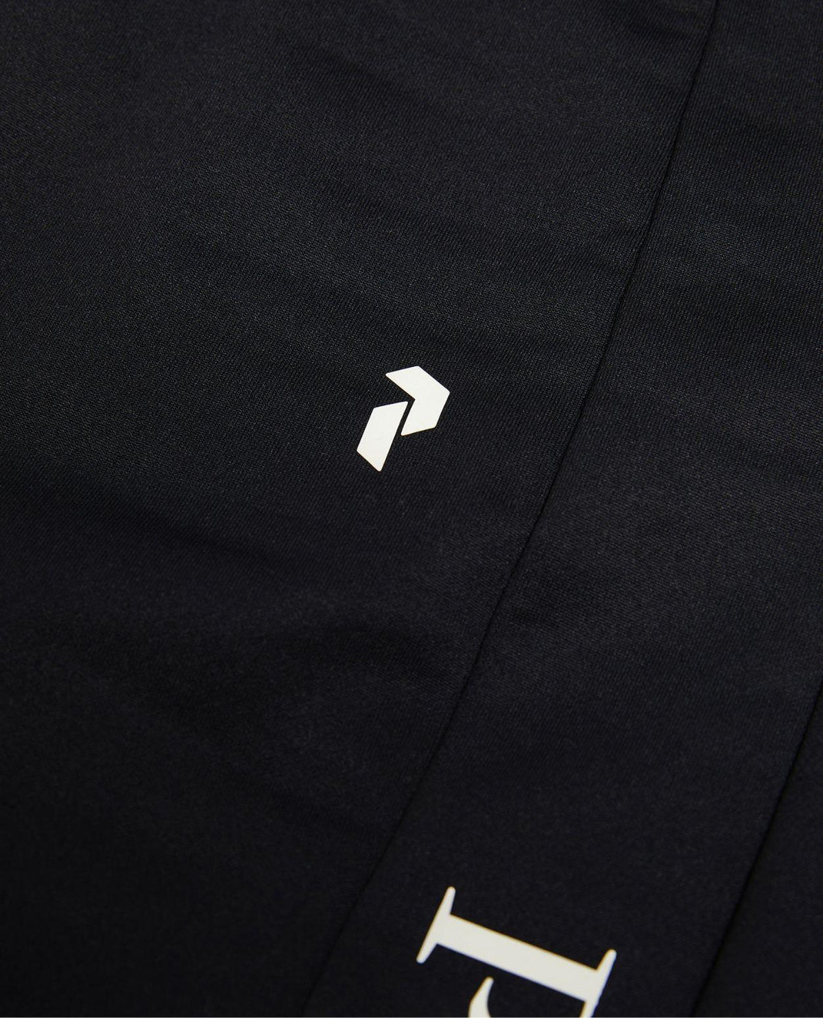Närbild på Peak Performance Rider Essentials Pants Women i svart med tryckt logotyp.
