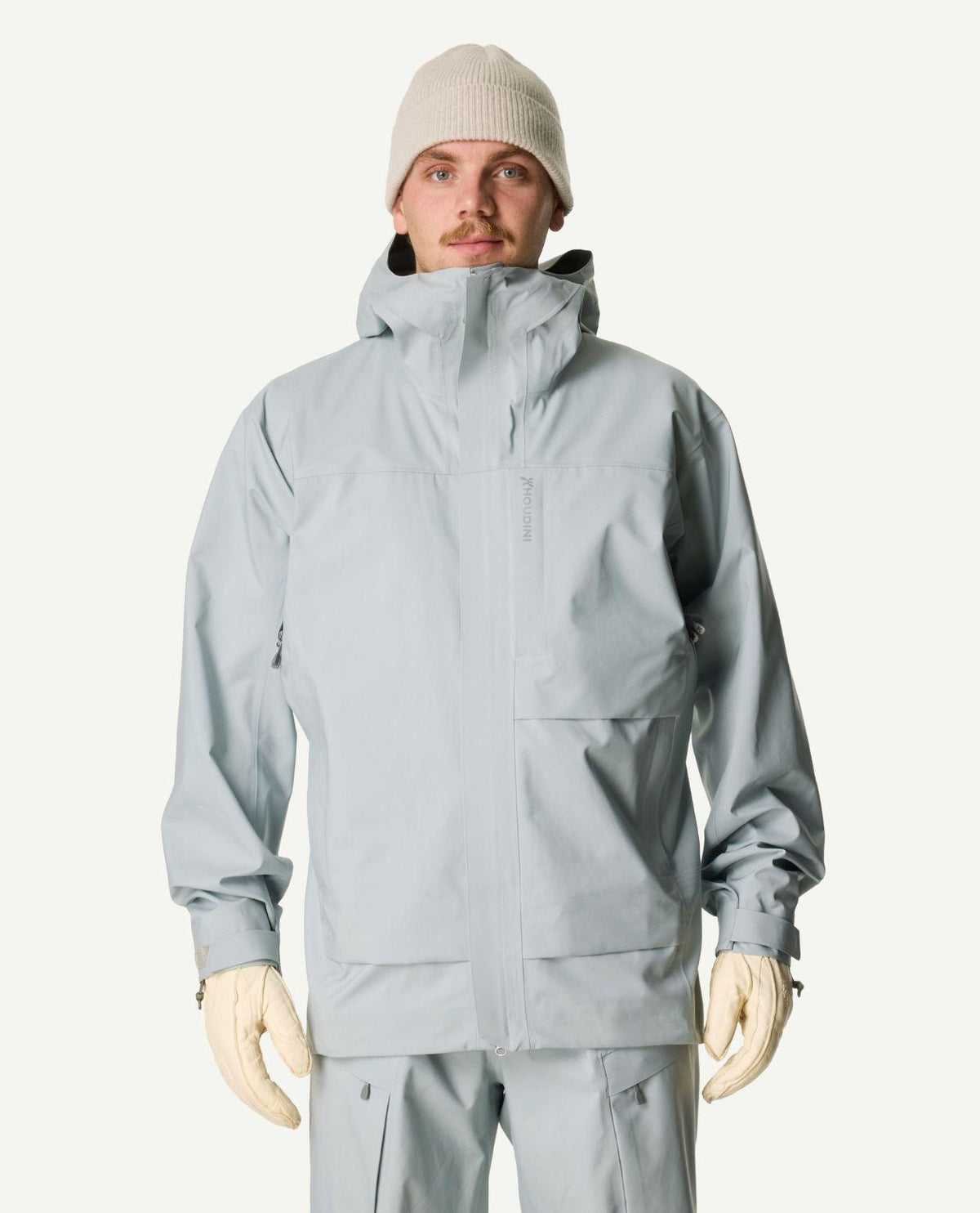 Manlig skidåkare iförd den grå skidjackan Houdini Rollercoaster Jacket II samt mössa och handskar.