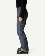 Houdini Ride Pants II dam i blått sett från sidan på en skidåkare med pjäxorna på.
