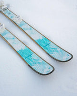 Head Kore 93 Ti Women allmountainskidor i vit design med turkosa detaljer liggandes i snö.