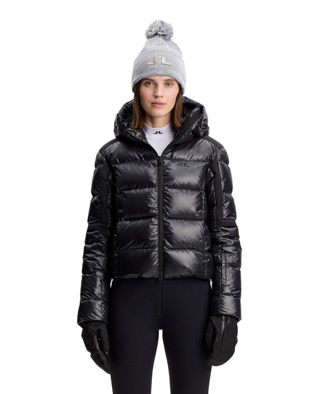 J.Lindeberg Nerina Down Jacket Women i svart, visad framifrån på modell med mössa och skidjacka.