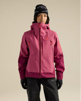 Kvinna i rosa skidjacka från Arc'teryx med huva, blixtlås och fickor.