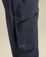 Närbild på Arc'teryx skidbyxor i mörkblått med en snedställd ficka med dragkedja och broderad logotyp på benet.