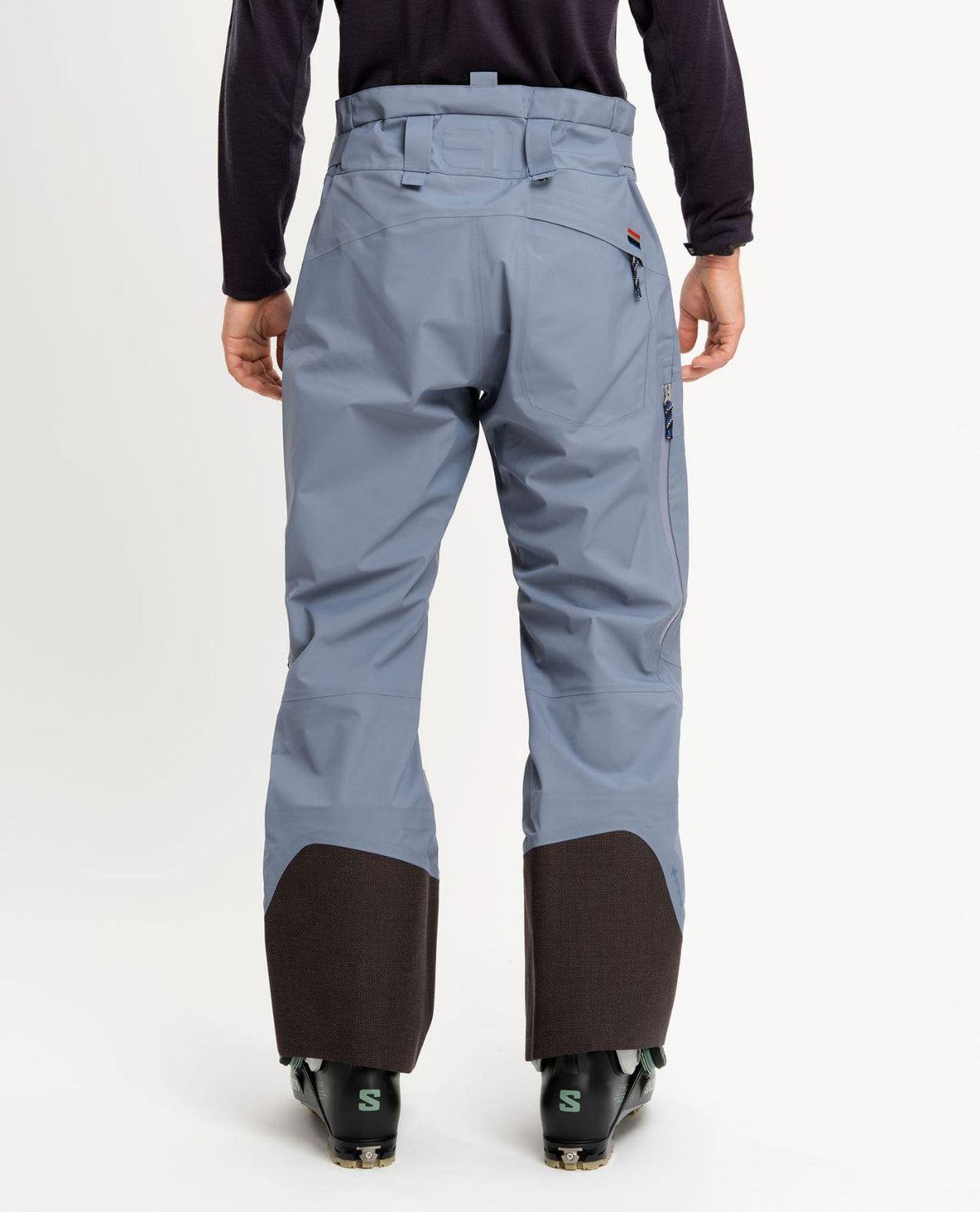 Elevenate Pure Pants Men i färgen Blue Flint bakifrån, hållbara GORE-TEX-skidbyxor med förstärkta benslut.