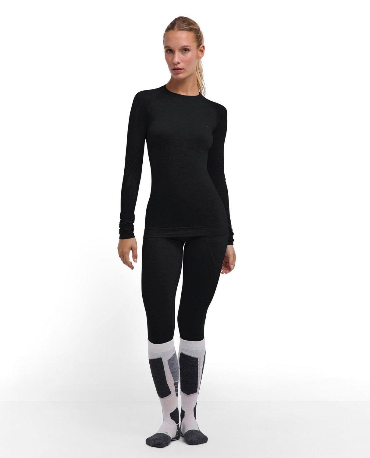 Kvinna i svart Falke Wool-Tech Light Longsleeved Shirt och matchande underställsbyxor.