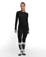 Kvinna i svart Falke Wool-Tech Light Longsleeved Shirt och matchande underställsbyxor.
