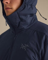 Närbild på Arc'teryx Atom Hoody mellanlager för herrar i färgen black sapphire med uppdragen huva och dragkedja uppdragen till hakan.