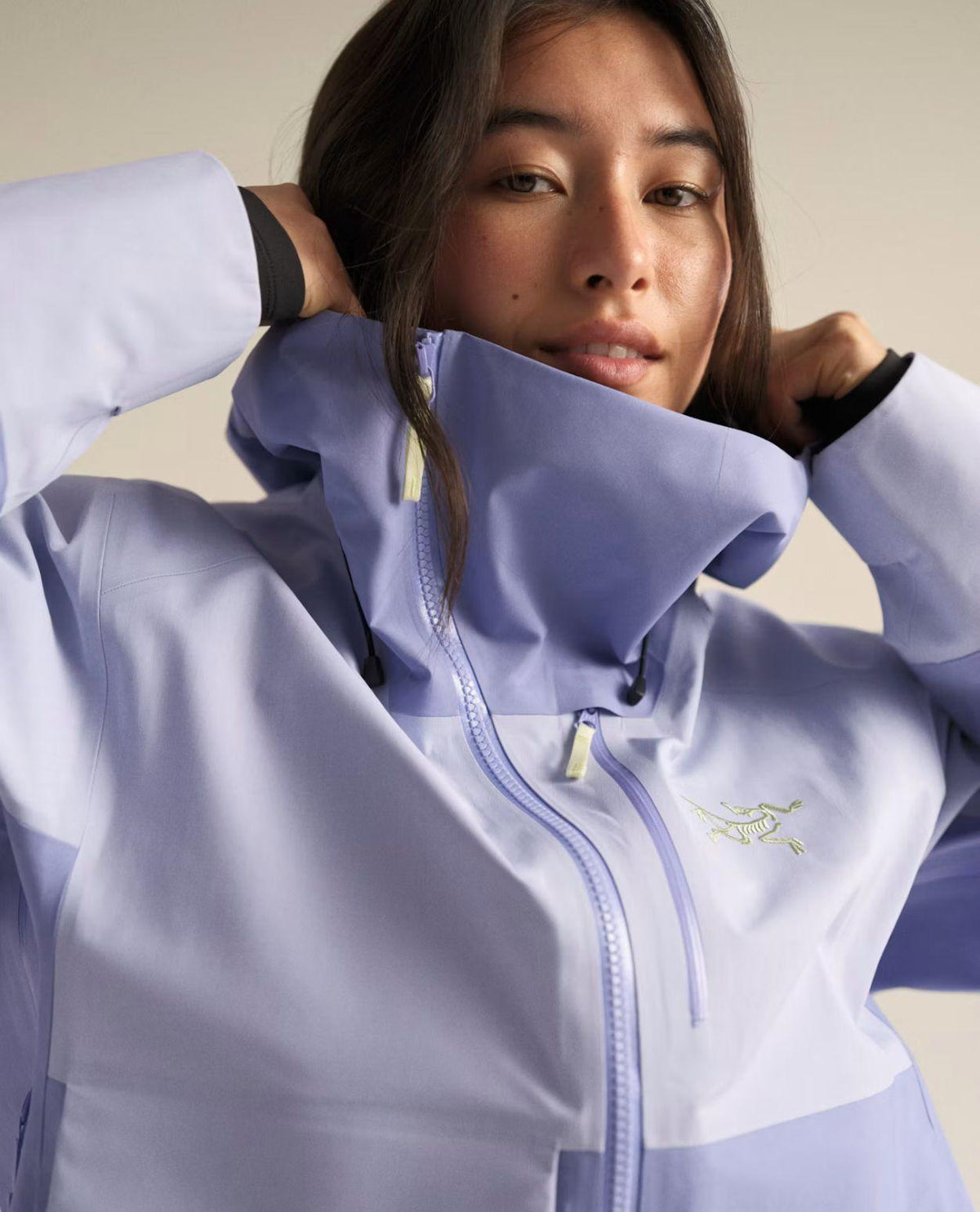 Kvinna iklädd Arc'teryx Sidewinder skidjacka i lila med den ikoniska asymmetriska dragkedjan.